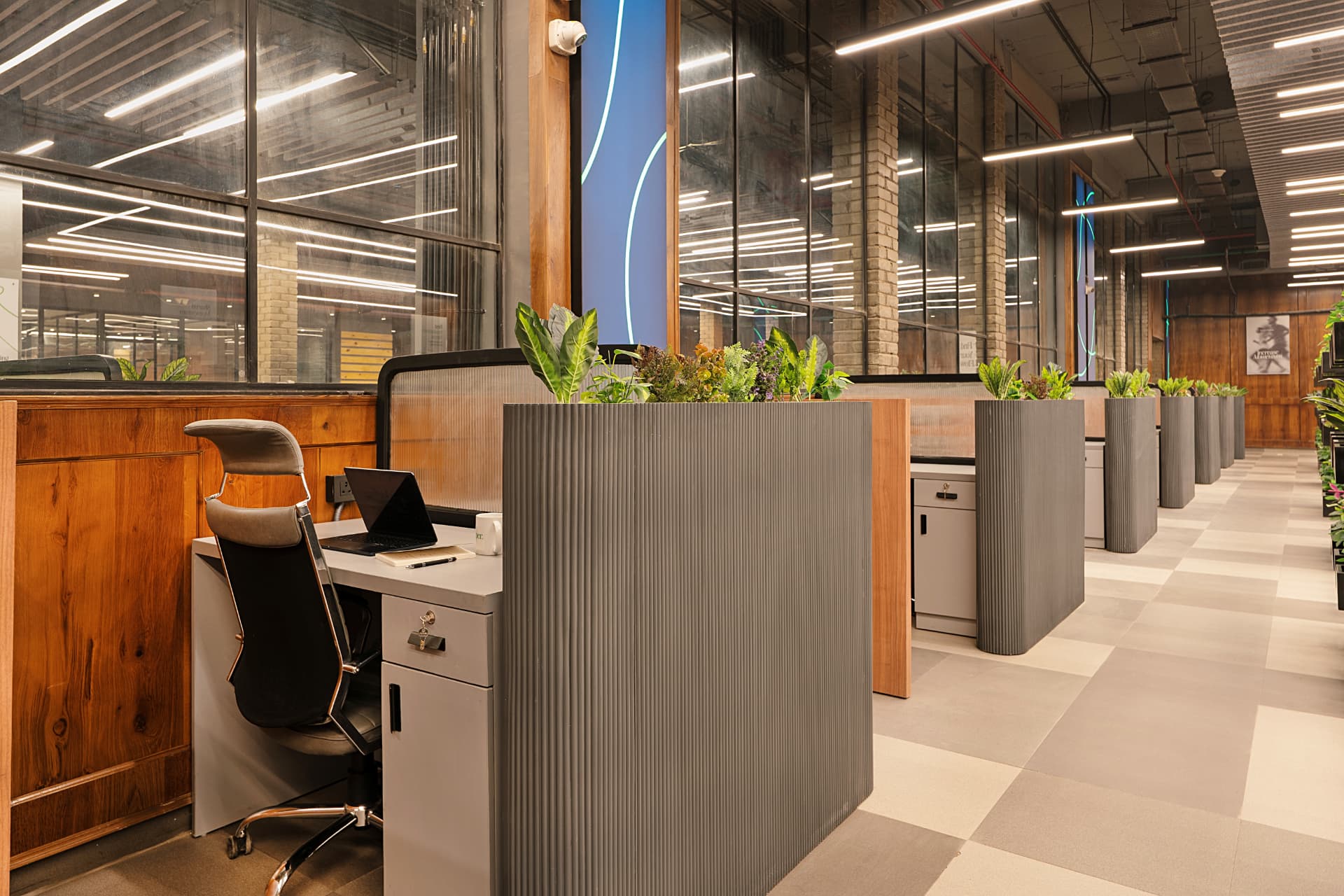 Private desk beside fluted planters and glazed partitions