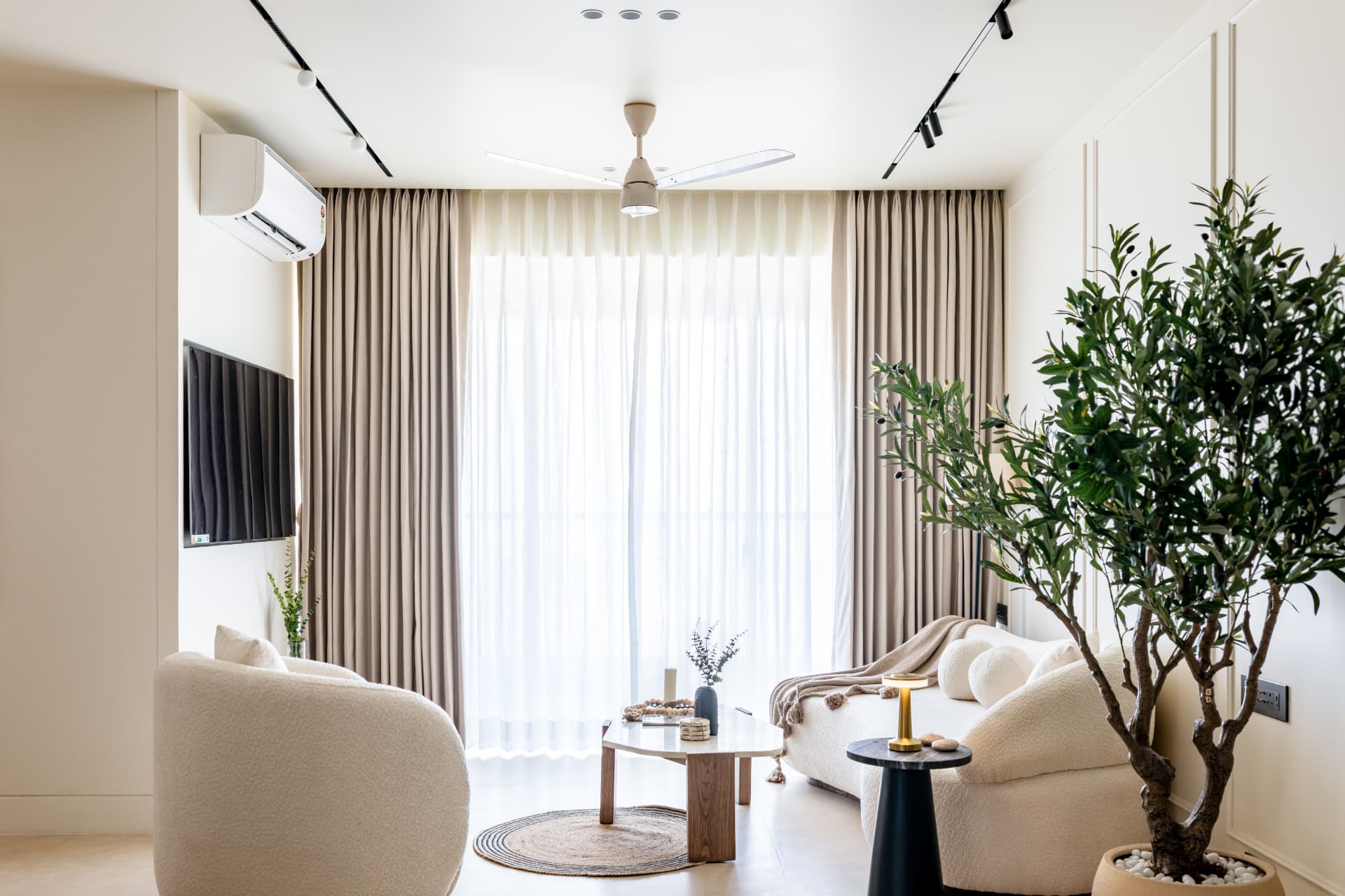 Living room in ivory with curved bouclé seating and floor-length linen drapes