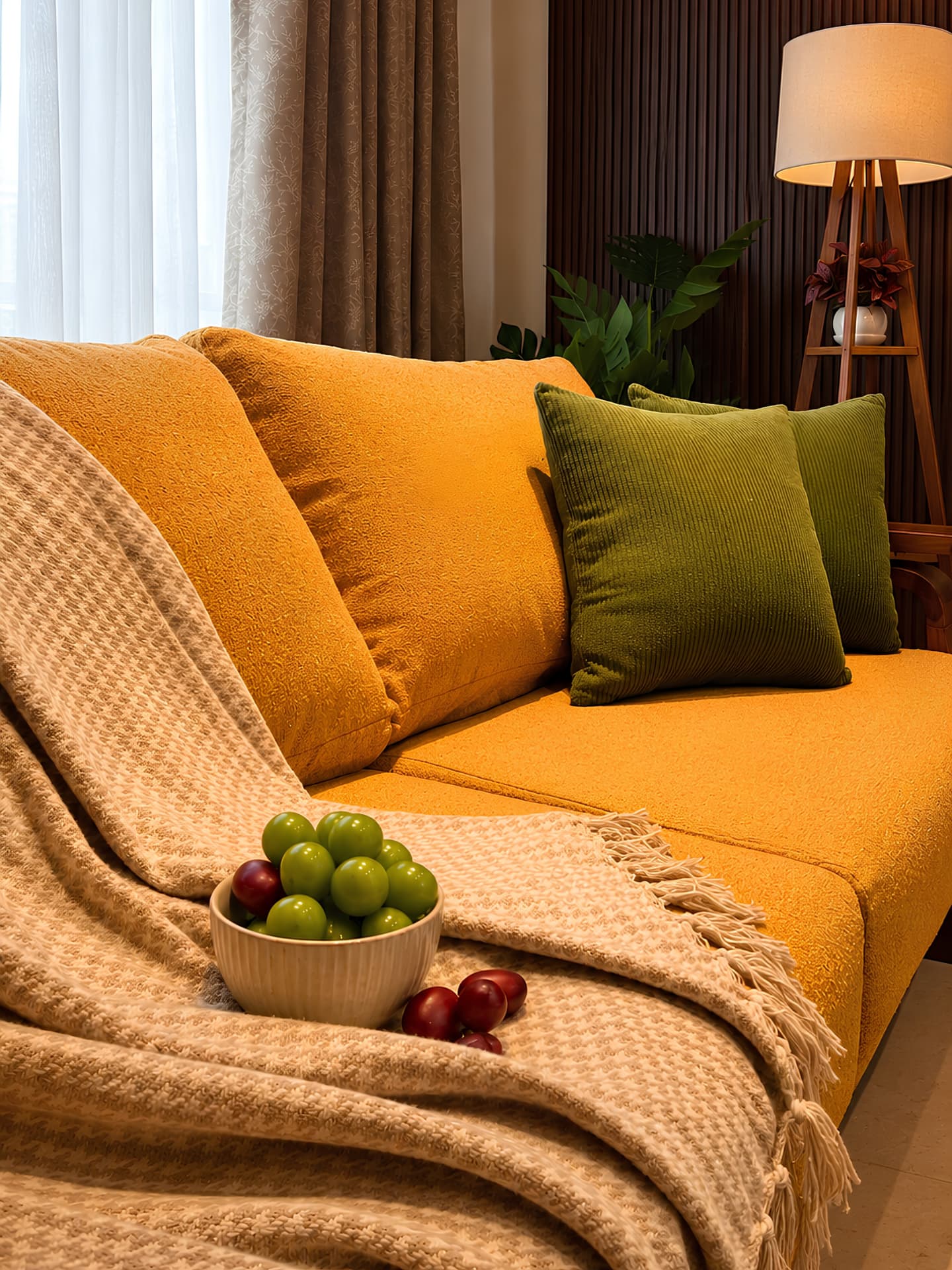 Close view of the mustard sofa with olive corduroy cushions and woven throw